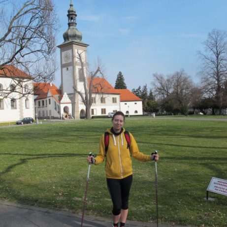 Autorka bloga stoi z kijkami do nordic walking na tle żółto-białego zamku w Zbraslawiu.